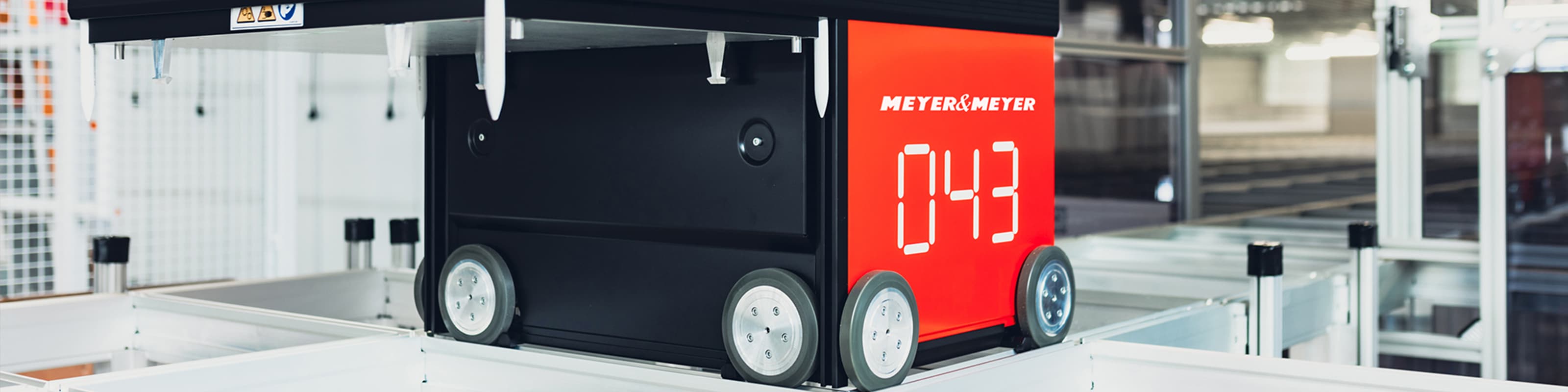 Autonomes Transportfahrzeug mit roter Meyer & Meyer-Beschriftung und Nummer 043 in einem Logistikzentrum