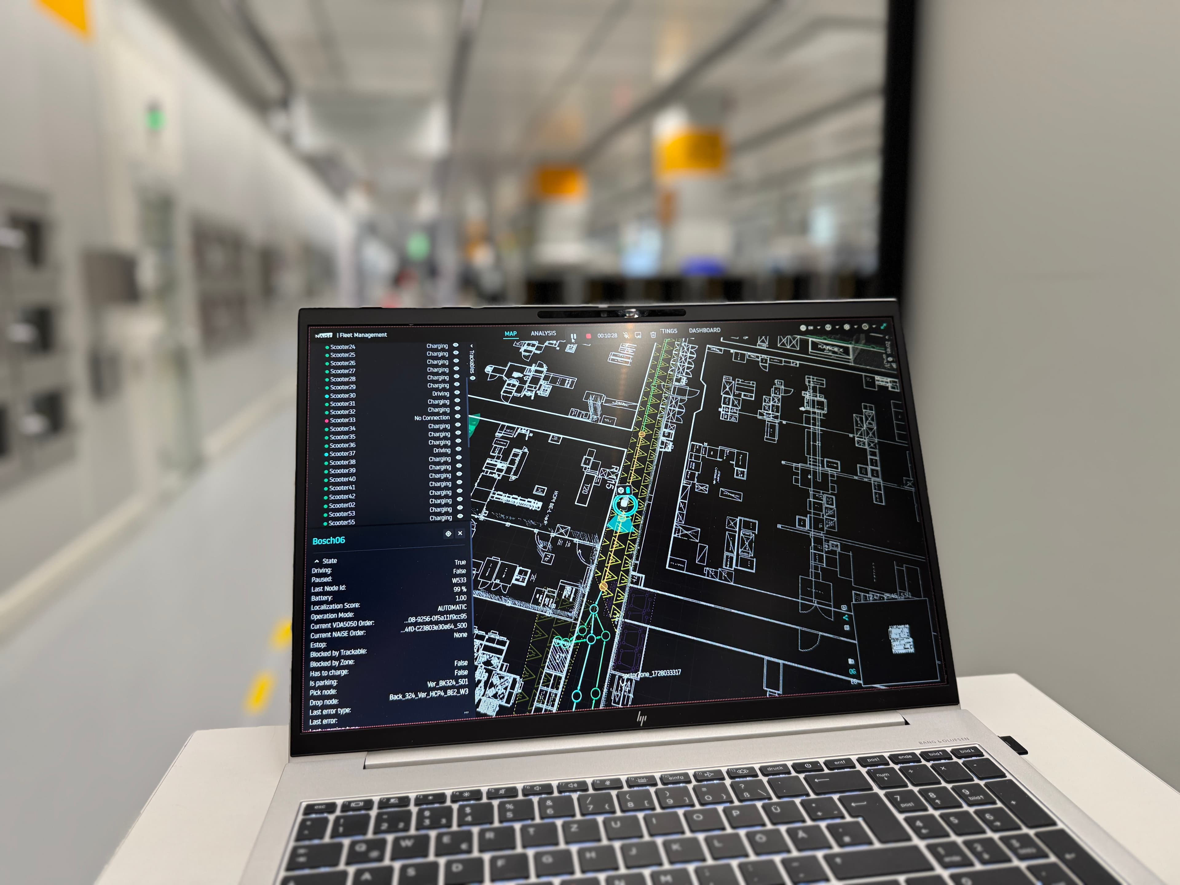 Ein Laptop zeigt einen Grundriss einer Logistikanlage in einem hell erleuchteten, modernen Flur mit unscharfem Hintergrund.